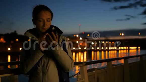 晚上在游轮甲板上使用垂直智能手机的女人视频的预览图