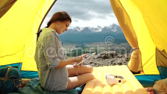 女人微笑着在帐篷上用平板电脑视频的预览图
