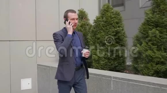 一个年轻的商人走在街上通过电话交谈视频的预览图