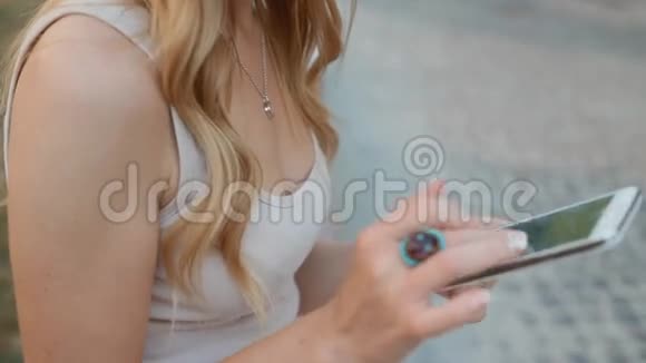 年轻的金发女人在户外用电话视频的预览图