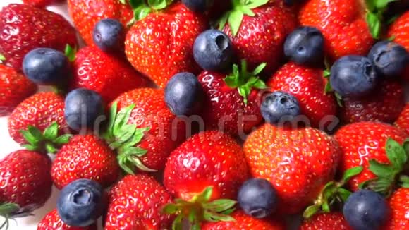 红色成熟的花园草莓和蓝莓浆果在白色桌子上旋转背景美丽视频的预览图