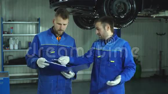 两名身穿蓝色制服的汽车修理工为汽车的全面诊断做准备视频的预览图