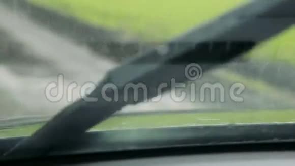 绿色田野上的雨透过汽车的挡风玻璃观看视频的预览图