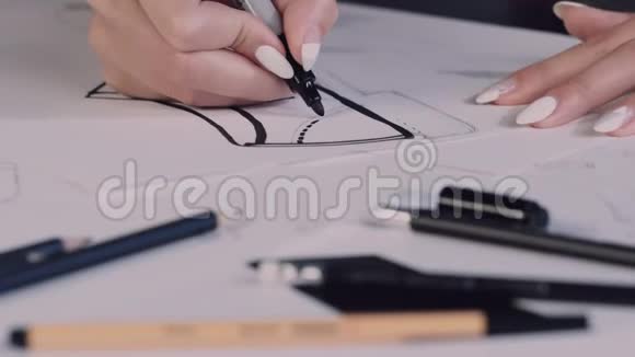 女人坐在办公室的桌子旁拿着铅笔在纸上画出鞋子的草图视频的预览图
