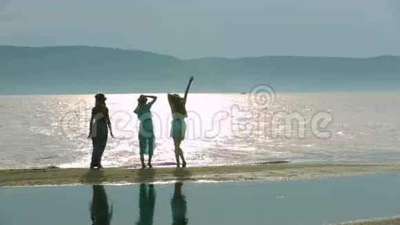 派对和人的概念一群微笑的少女在海滩上跳跃三个年轻女人到处乱跑的剪影视频的预览图