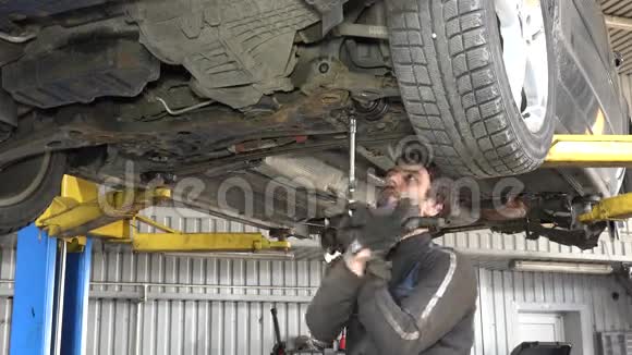 男式汽车修理工带扳手在车库下工作视频的预览图