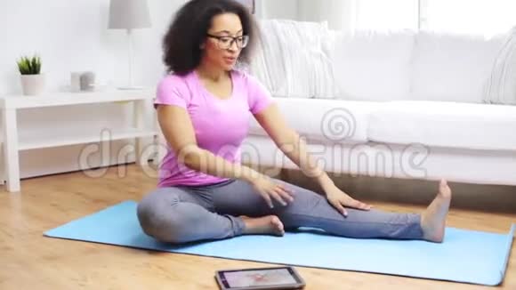 带平板电脑的非洲女性在家锻炼视频的预览图