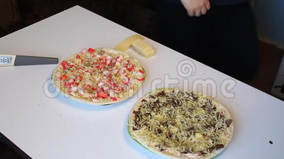 准备披萨这个人用螃蟹棒和树叶在披萨上把奶酪涂在烤架上视频的预览图
