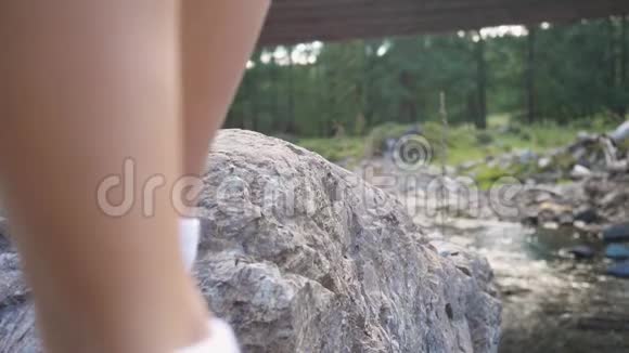 在阳光明媚的夏日里一位女旅行家慢吞吞地踩在山间的石头上1920x1080个视频的预览图