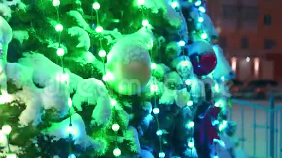 在下雪的冬夜城市广场上有发光的花环和装饰的大型圣诞树特写镜头照相机视频的预览图