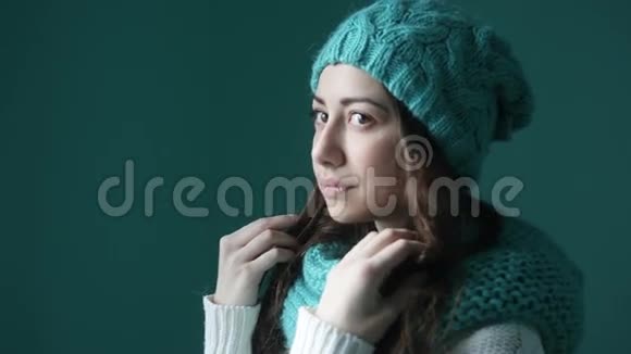 戴着绿松石针织帽子和围巾的漂亮年轻女子视频的预览图