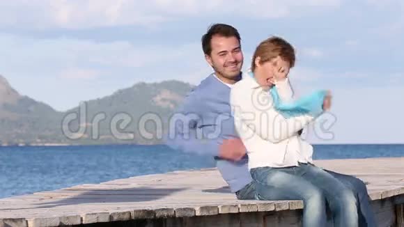 坐在沙滩上嬉戏的年轻夫妇视频的预览图