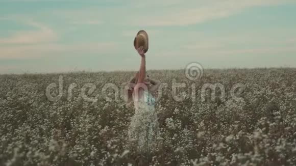 戴着帽子的美女走在田野里开着田野的花视频的预览图
