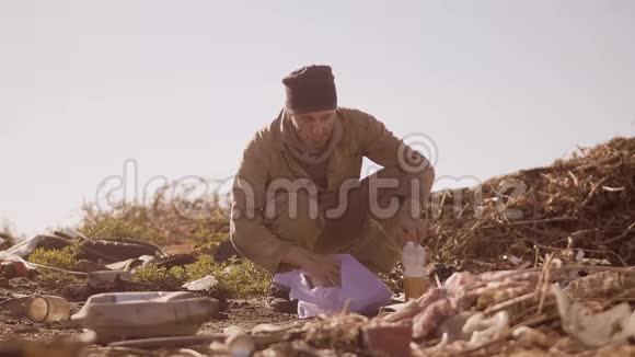 一个肮脏的无家可归的饥饿男人在垃圾堆里吃食物走路去找食物慢了下来的肖像视频的预览图