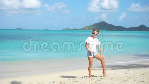 带着一瓶防晒霜的小女孩坐在热带海滩上视频的预览图