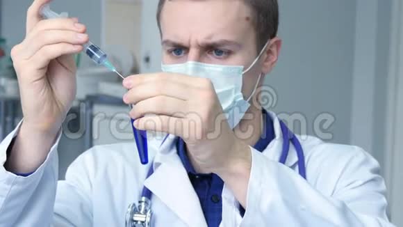 年轻的白种人医生把一种蓝色的液体从注射器倒到管子上的肖像视频的预览图