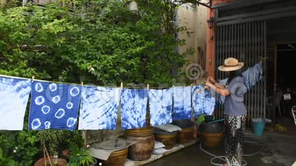 泰国妇女在阳光下系蜡染靛蓝颜色的悬挂工艺干衣视频的预览图