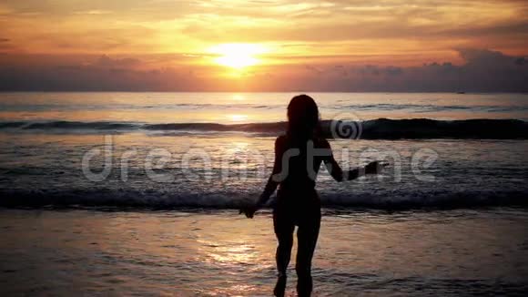 日落时分在海面上奔跑的女性剪影视频的预览图