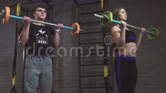在健身房锻炼杠铃肌肉的男人和女人视频的预览图