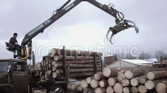 在锯木厂卡车爪式装载机从重型卡车上卸下木材视频的预览图