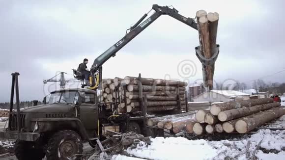 起重机械装载机在锯木厂从重型卡车上卸下木材视频的预览图