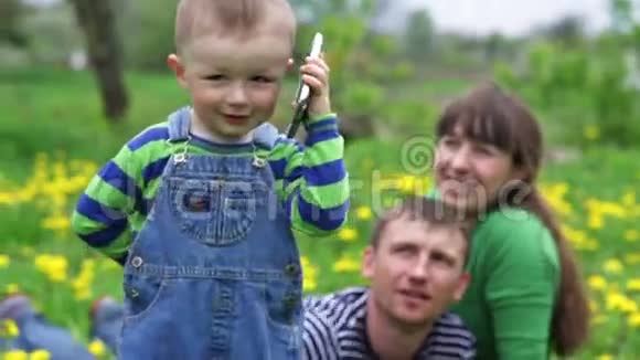 小男孩在春日草地上打电话视频的预览图