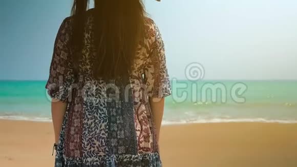 海滩上穿着蓝色裙子的女孩看着海洋近距离射击视频的预览图