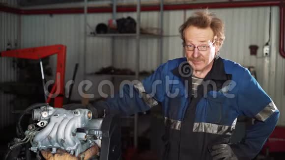 一个年轻漂亮的汽车修理工在汽车车间的肖像在一辆破车的背景上概念机器视频的预览图