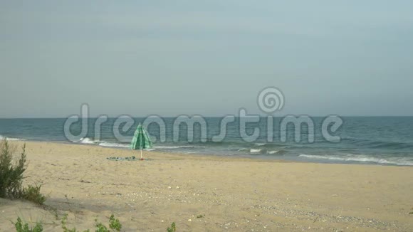 孤独的海滩伞在海边的沙滩上风吹在伞和毛巾上视频的预览图