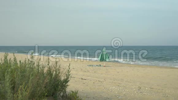 孤独的海滩伞在海边的沙滩上风吹在伞和毛巾上视频的预览图