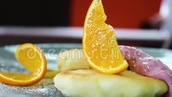 准备好的芝士蛋糕盘子上有两个酱汁和一片橘子视频的预览图