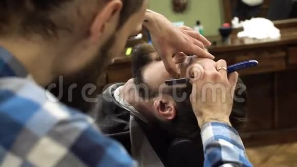 专业理发师用剃刀刮客户的胡子非常集中4K视频的预览图