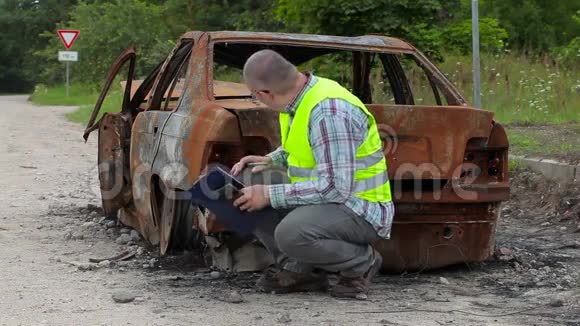 检查人员在路边烧毁的汽车残骸附近进行检查和书写视频的预览图