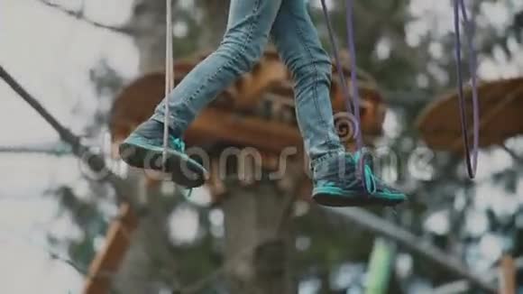 小男孩在树林中穿过电缆线路冒险公园里的极限运动视频的预览图