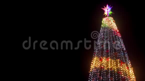 在下雪的冬夜城市广场上有发光的花环和装饰的大型圣诞树特写镜头发光视频的预览图