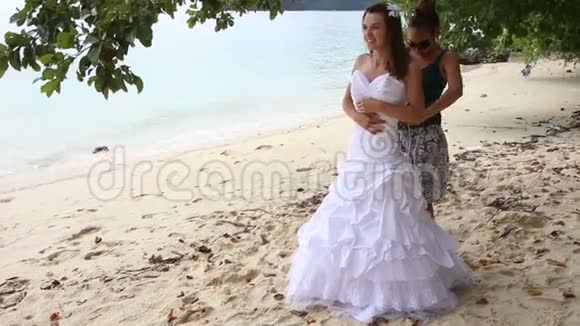 助理协助新娘在沙滩上系婚纱礼服视频的预览图