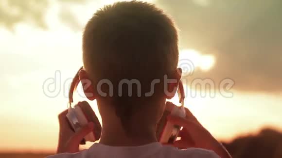 日落时分男孩在田野里戴着耳机视频的预览图