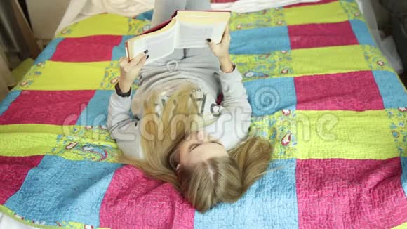 漂亮的年轻女人在家里的床上看书在家学习视频的预览图