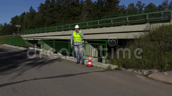 公路施工工人在公路附近的桥梁上打电话视频的预览图