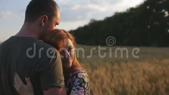 一对拥抱亲吻然后在日落时漫步在开阔的金色田野视频的预览图