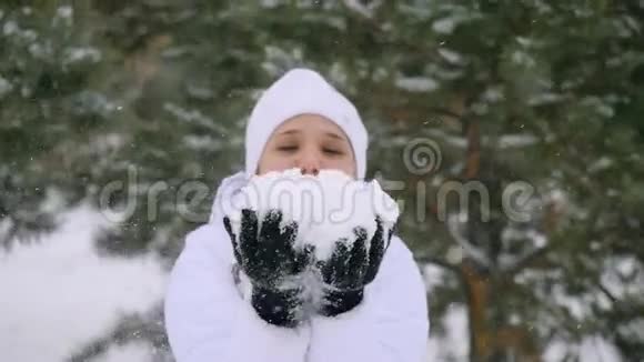年轻女子在降雪时吹雪花在缓慢的运动中享受冬天的时光1920x1080视频的预览图
