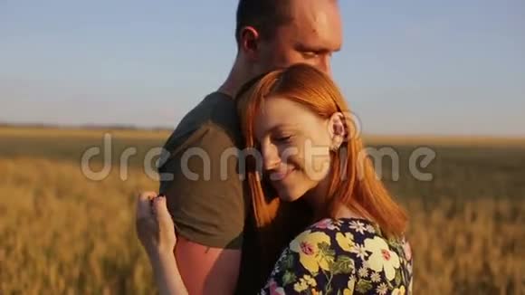 一对拥抱亲吻然后在日落时漫步在开阔的金色田野视频的预览图