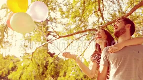 快乐的情侣在公园里拥抱手里拿着气球视频的预览图