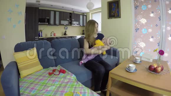 妈妈把刚出生的婴儿摆在手上坐在沙发上吃苹果4K视频的预览图