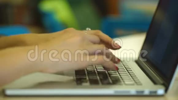 在室内的笔记本电脑上女性手按短信的特写镜头坐在图书馆的楼梯和视频的预览图