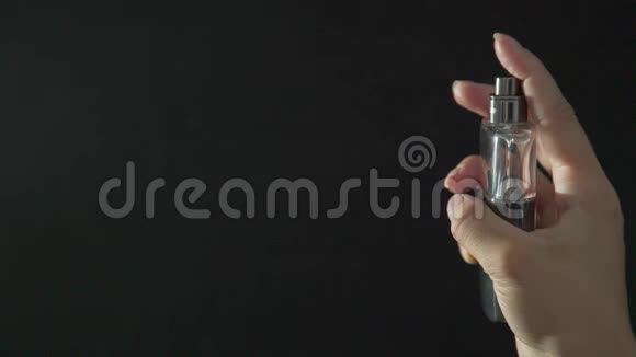 女性手拿着一瓶香水喷它去感受芬芳视频的预览图