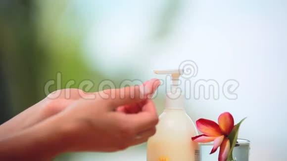 奶油在雌花和绿叶旁的双手上的应用视频的预览图