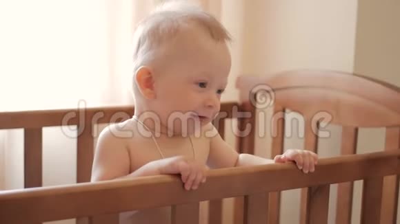 婴儿站在家里的床上婴儿男孩站在床上的肖像宝贝的眼睛在找妈妈视频的预览图