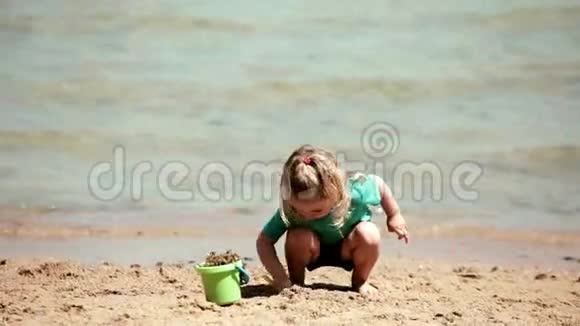 小女孩玩水桶和铲子挖沙子视频的预览图