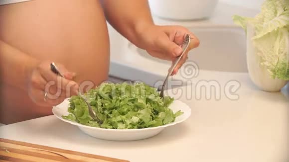 孕妇在厨房的碗里拌沙拉视频的预览图
